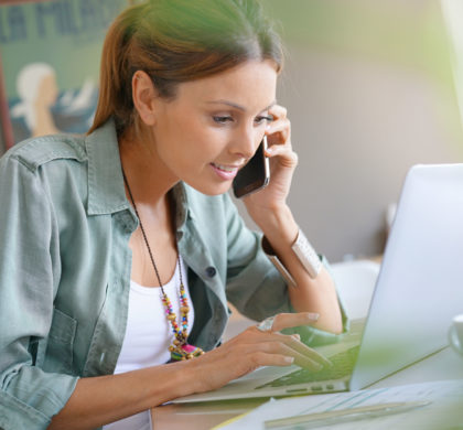 Woman working from home on laptop and talking on phone