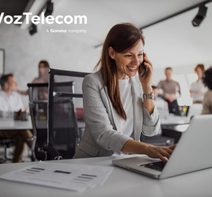 Brunette woman working hard, using laptop while talking to someone over the phone.