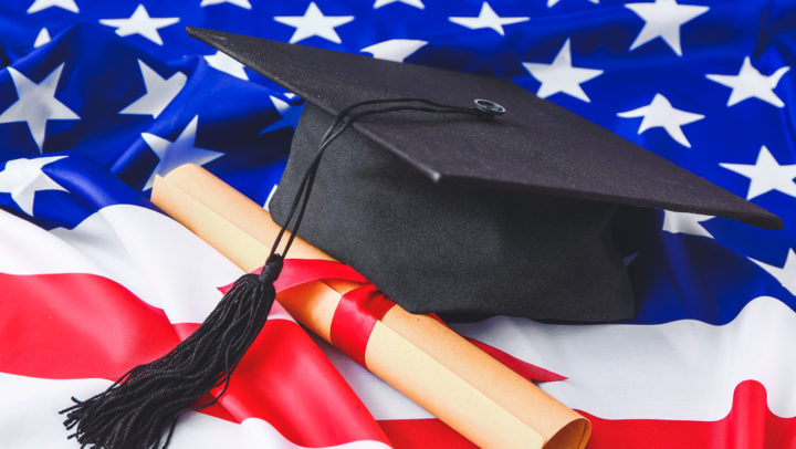 Graduation hat and diploma on USA flag