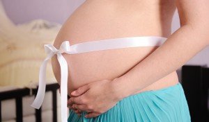 Pregnant woman abdomen with white bow.