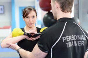 Personal trainer helping young woman with kettle bells